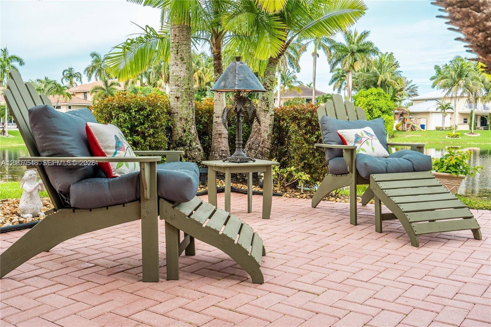 Patio featuring red brick pavers, mature palm trees, and water frontage