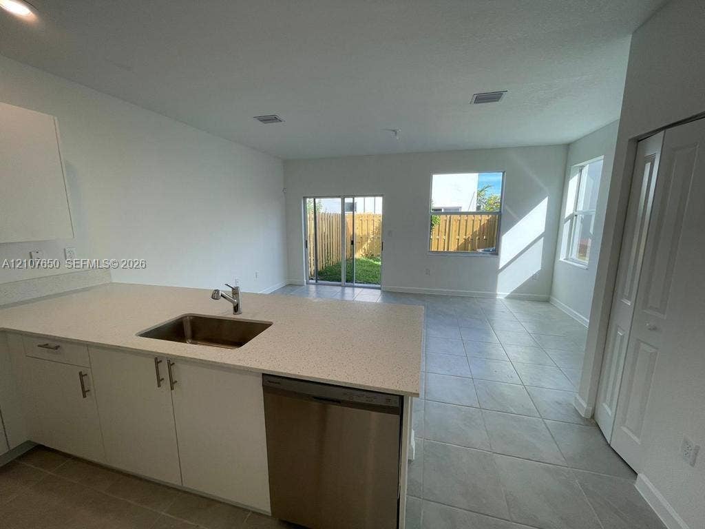 1787 SE 26th Terrace, Homestead, Homestead, FL 33035 Kitchen featuring an island with a stainless steel undermount sink, quartz countertops, white cabinetry with brushed-metal hardware, stainless steel dishwasher, and tile flooring