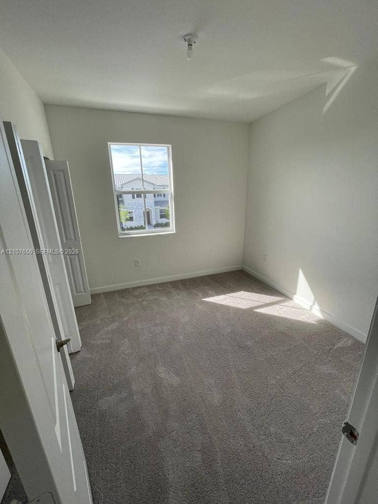 1787 SE 26th Terrace, Homestead, Homestead, FL 33035 Neutral-toned carpeting, crisp white wall finish, single-hung window with a vertical muntin, and bifold closet doors