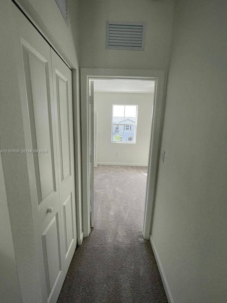 1787 SE 26th Terrace, Homestead, Homestead, FL 33035 Hallway featuring bi-fold closet doors and neutral carpeting