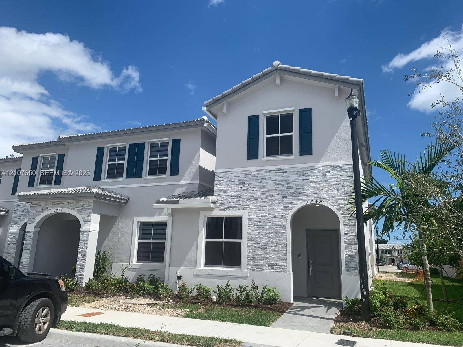 1787 SE 26th Terrace, Homestead, Homestead, FL 33035 Two-story exterior featuring a light gray stucco facade with stone veneer accents, arched entryways, dark-toned shutters, and a tiled roof