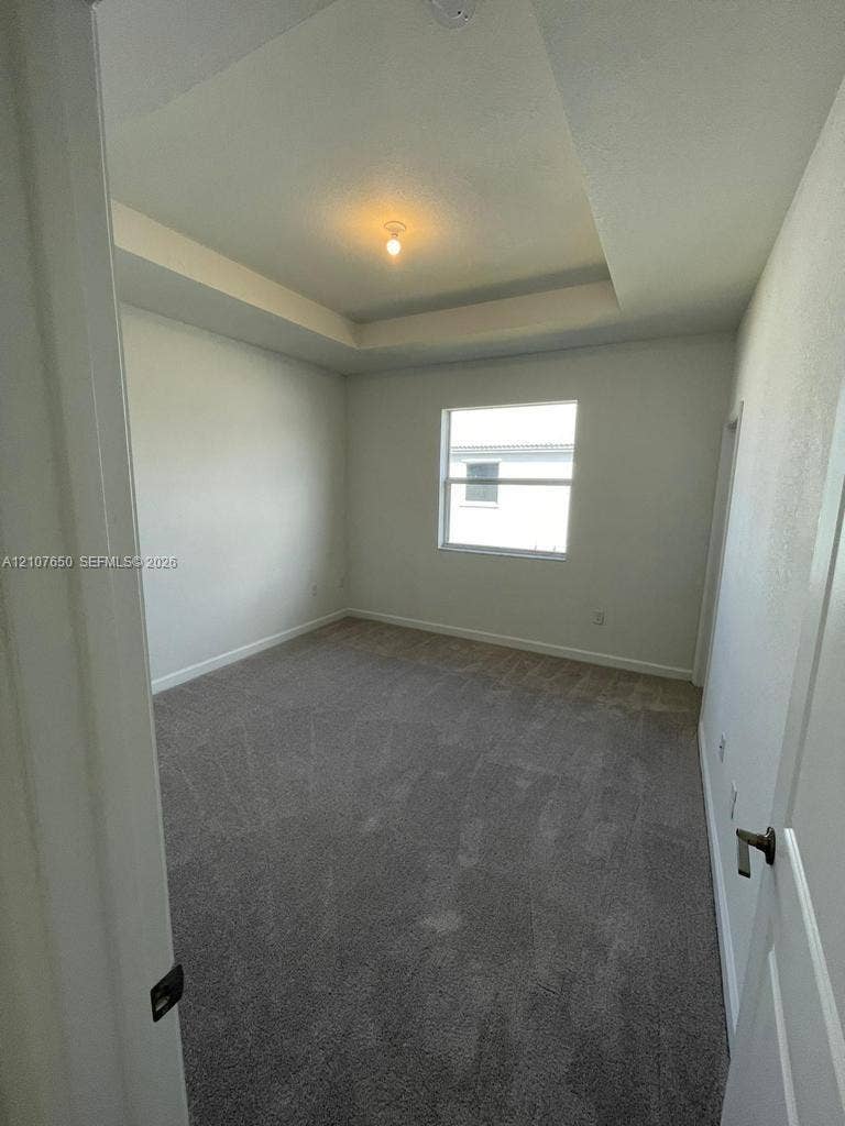 1787 SE 26th Terrace, Homestead, Homestead, FL 33035 Tray ceiling, neutral wall tones, plush wall-to-wall carpeting, single-pane window, and central overhead lighting