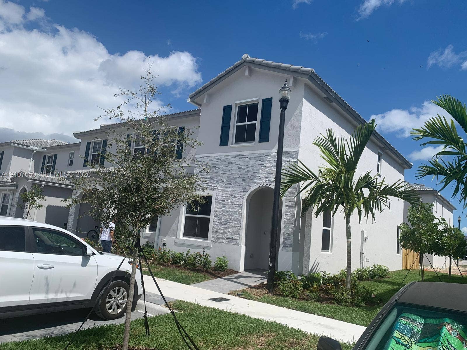 1787 SE 26th Terrace, Homestead, Homestead, FL 33035 Two-story exterior featuring a light-toned stucco finish, stacked stone facade detailing, arched entryway, and dark blue shutters