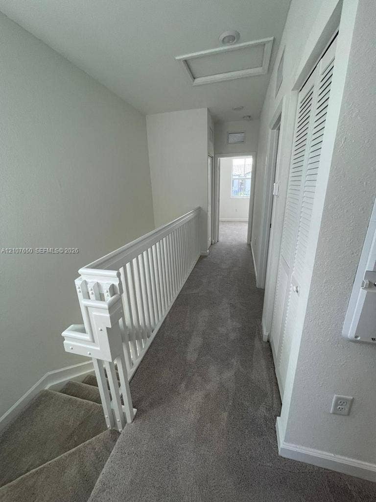 1787 SE 26th Terrace, Homestead, Homestead, FL 33035 Hallway featuring neutral carpeting, white spindle railing, and louvered closet doors