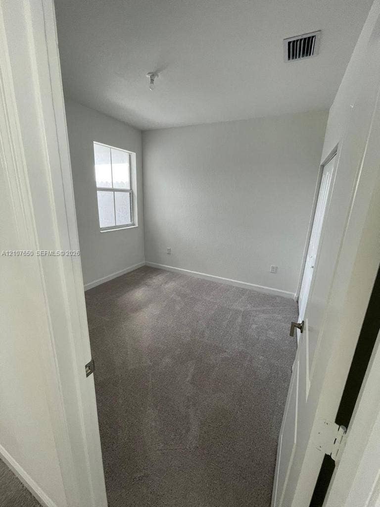 1787 SE 26th Terrace, Homestead, Homestead, FL 33035 Room featuring neutral-toned carpeting, crisp white walls, and a single-pane window with white trim