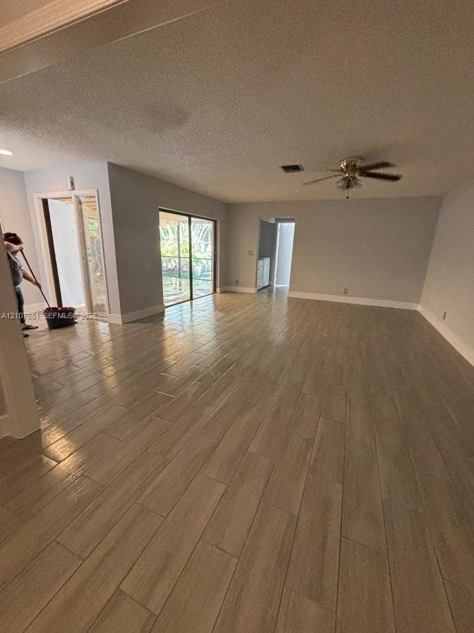 Spacious interior featuring wood-finish flooring, neutral wall paint, and a ceiling-mounted fan
