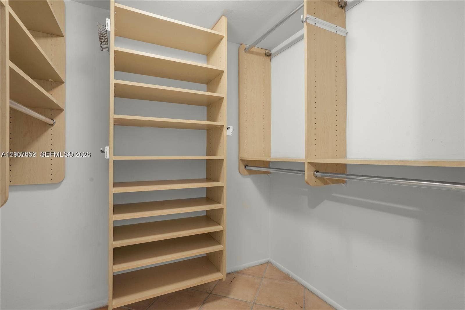 20500 W Country Club Drive, #607, Aventura, Aventura, FL 33180 Custom walk-in closet featuring light-toned wood-finish shelving, multi-level hanging rods, and tile flooring