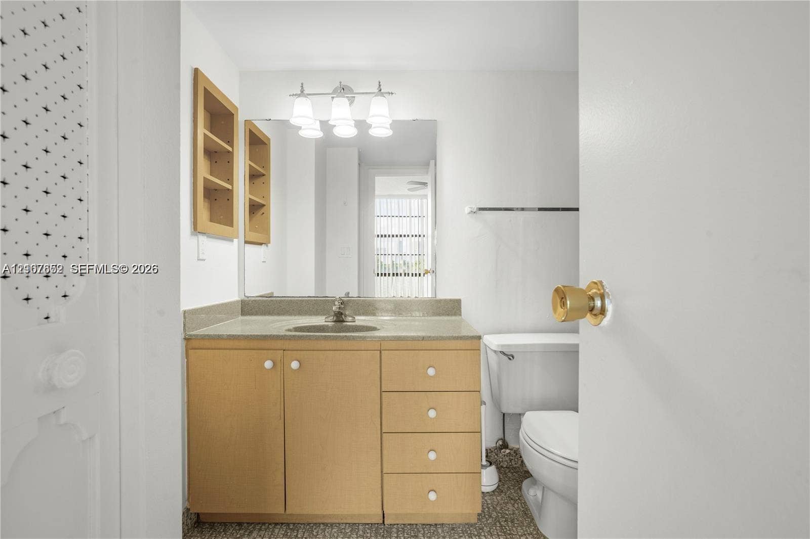 20500 W Country Club Drive, #607, Aventura, Aventura, FL 33180 Bathroom vanity featuring light wood-finish cabinetry, stone-style countertop, inset sink, large rectangular wall mirror, and built-in recessed shelving