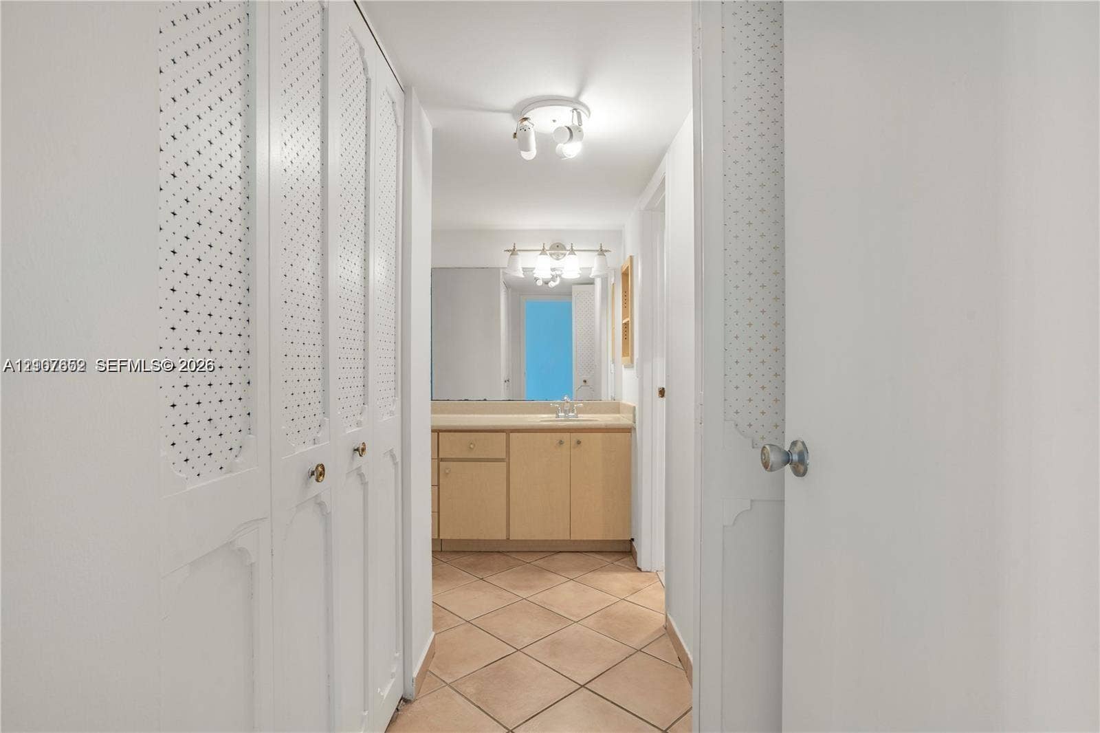 20500 W Country Club Drive, #607, Aventura, Aventura, FL 33180 Bathroom interior featuring wood-finish cabinetry, tile flooring, built-in storage closets with decorative metal grille inserts, and a dual-bulb vanity light fixture