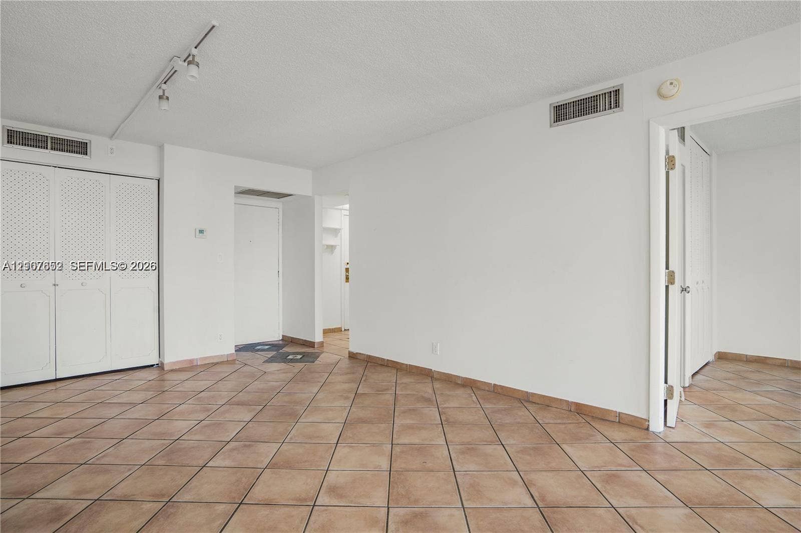20500 W Country Club Drive, #607, Aventura, Aventura, FL 33180 Open interior space featuring light-toned tile flooring, white bi-fold closet doors with decorative paneling, and adjustable track lighting