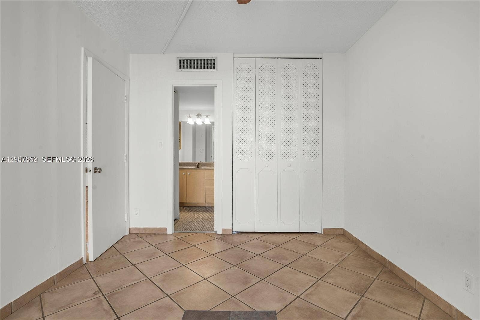20500 W Country Club Drive, #607, Aventura, Aventura, FL 33180 Interior space featuring neutral wall-to-wall tile flooring, white bi-fold closet doors, and a solid-core interior door