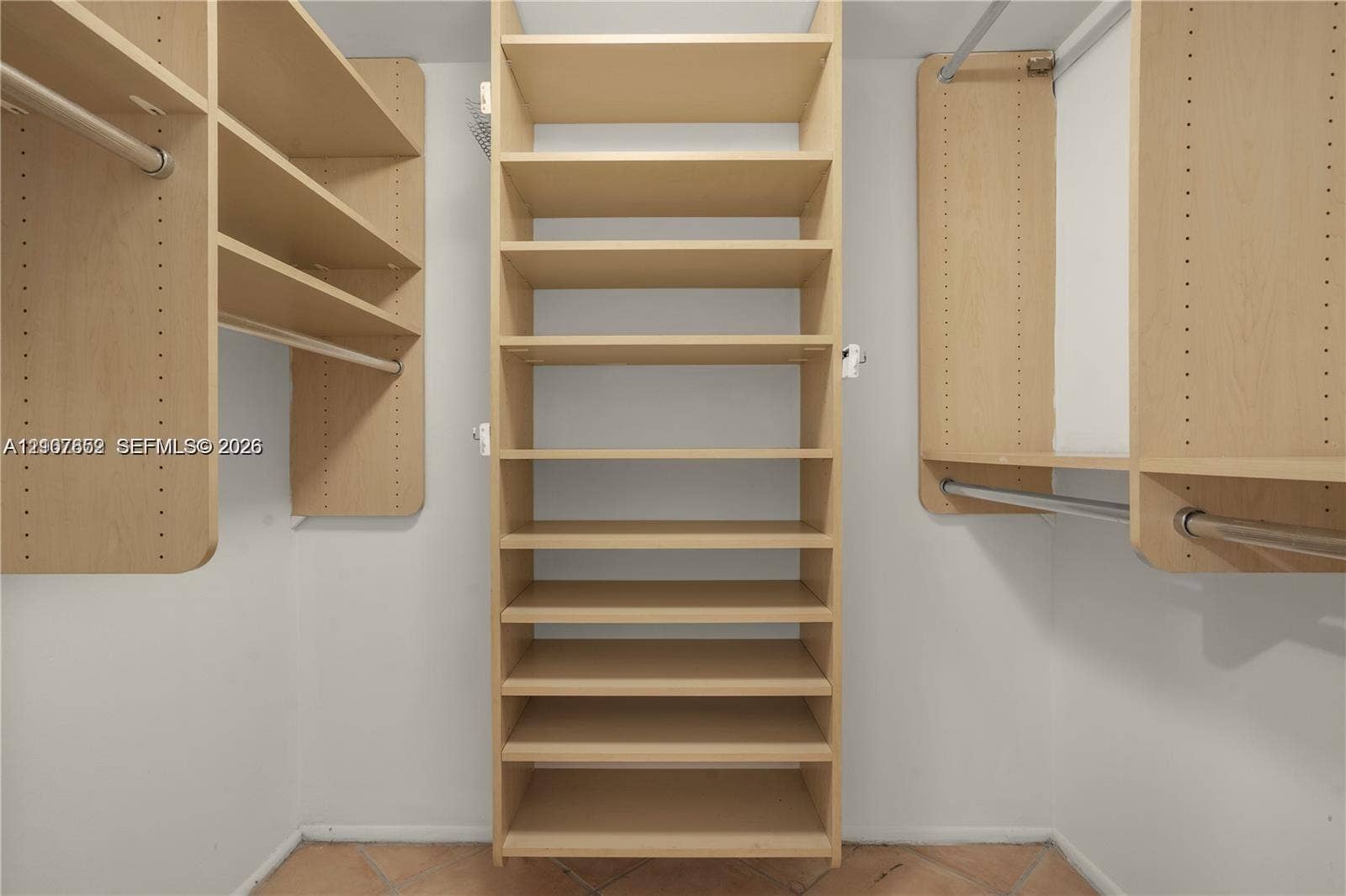20500 W Country Club Drive, #607, Aventura, Aventura, FL 33180 Walk-in closet featuring light wood-finish built-in shelving, vertical storage tower, dual metal garment rods, and tile flooring