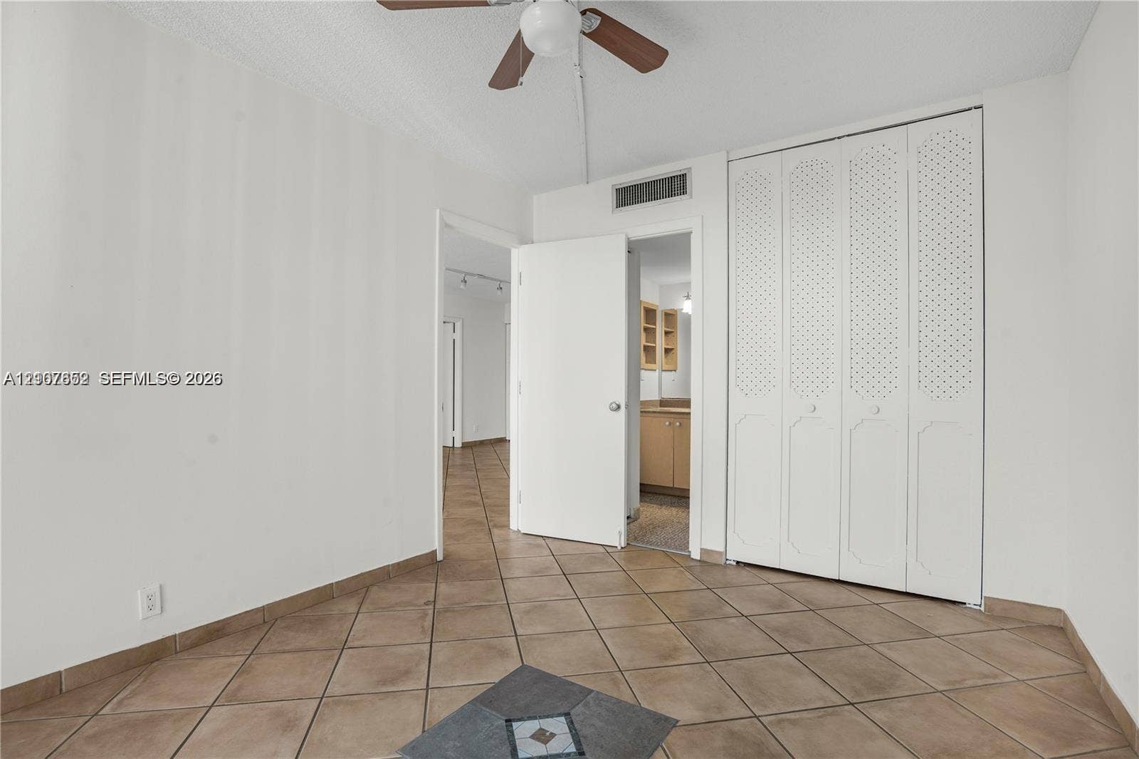 20500 W Country Club Drive, #607, Aventura, Aventura, FL 33180 Ceramic tile flooring with a central decorative inset, four-panel louvered closet doors, and a ceiling-mounted fan with wood-finish blades