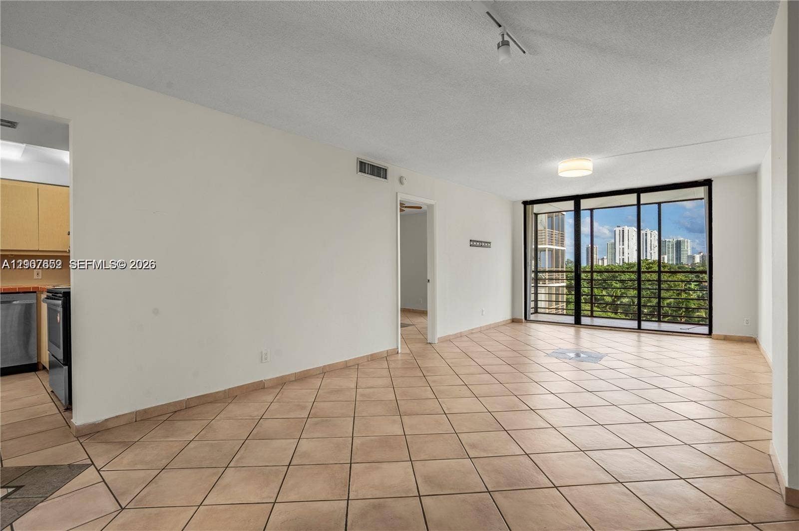 20500 W Country Club Drive, #607, Aventura, Aventura, FL 33180 Open living area featuring neutral ceramic tile flooring, floor-to-ceiling sliding glass doors, and recessed ceiling lighting