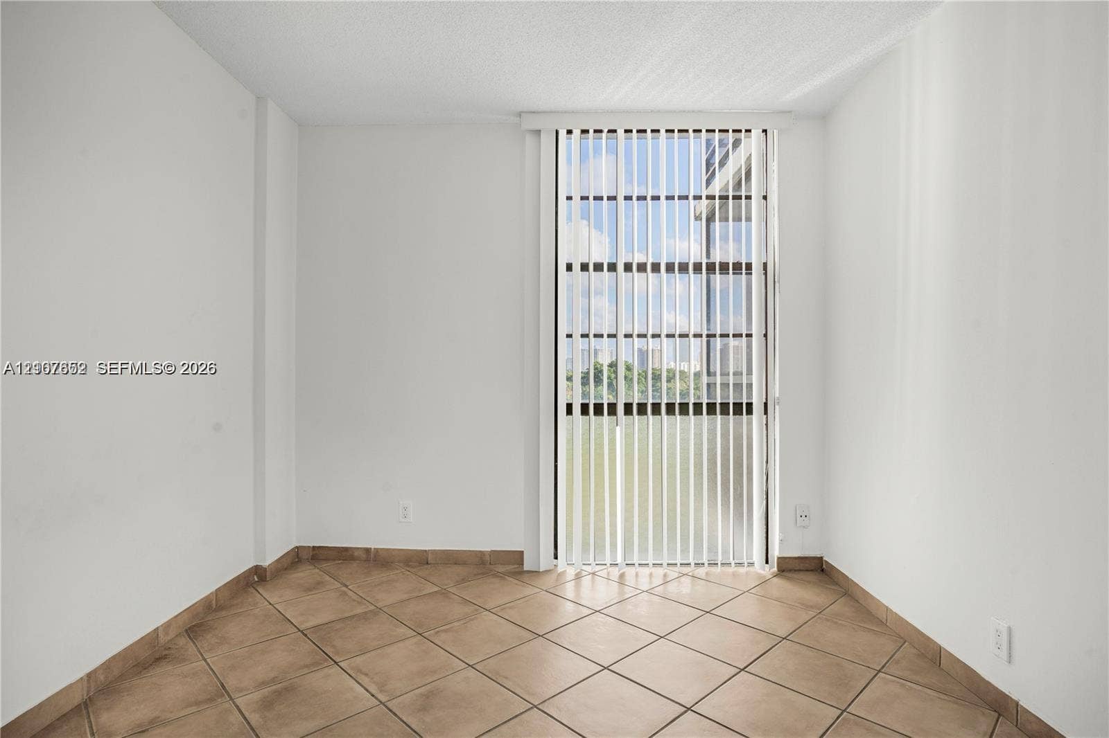 20500 W Country Club Drive, #607, Aventura, Aventura, FL 33180 Room featuring neutral wall finishes, tile flooring, and a vertical blind covering a full-height glass door