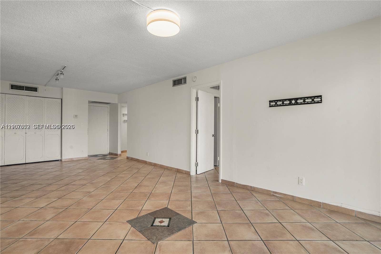 20500 W Country Club Drive, #607, Aventura, Aventura, FL 33180 Interior space featuring ceramic tile flooring with decorative inlay, built-in louvered-door cabinetry, and a flush-mount drum light fixture