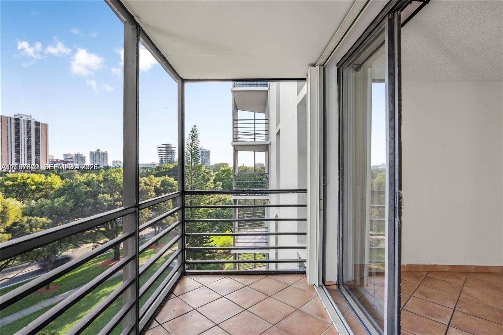 20500 W Country Club Drive, #607, Aventura, Aventura, FL 33180 Private balcony featuring terracotta tile flooring and black metal railings, enclosed by sliding glass doors