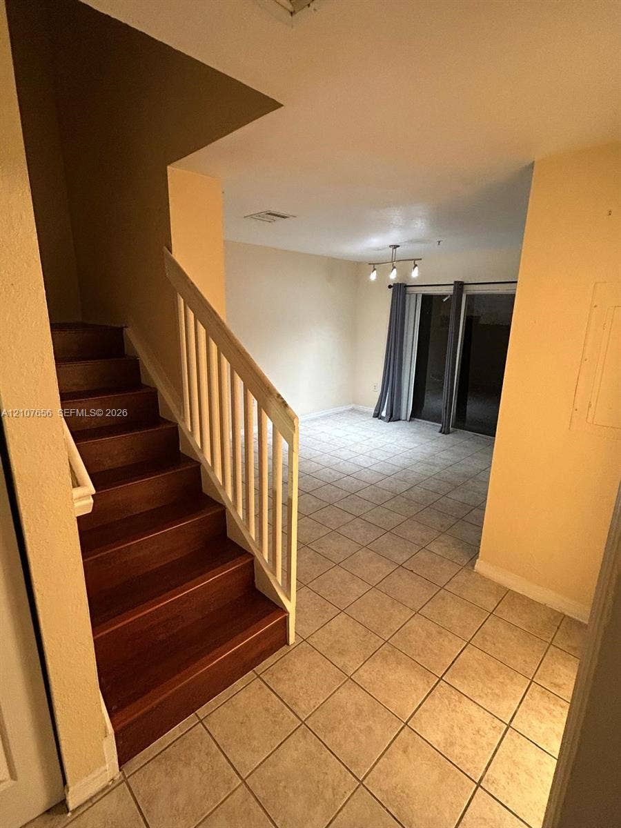 2088 NE 167th Street, #2-111, North Miami Beach, North Miami Beach, FL 33162 Staircase with wood-finish treads, white railing, ceramic tile flooring, and multi-bulb light fixture
