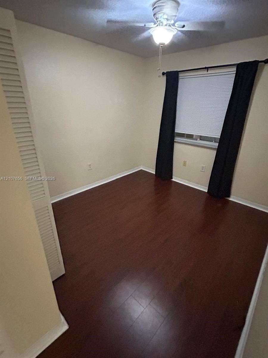 2088 NE 167th Street, #2-111, North Miami Beach, North Miami Beach, FL 33162 Room interior featuring wood-finish flooring, a ceiling fan with integrated lighting, and a closet with louvered bi-fold doors