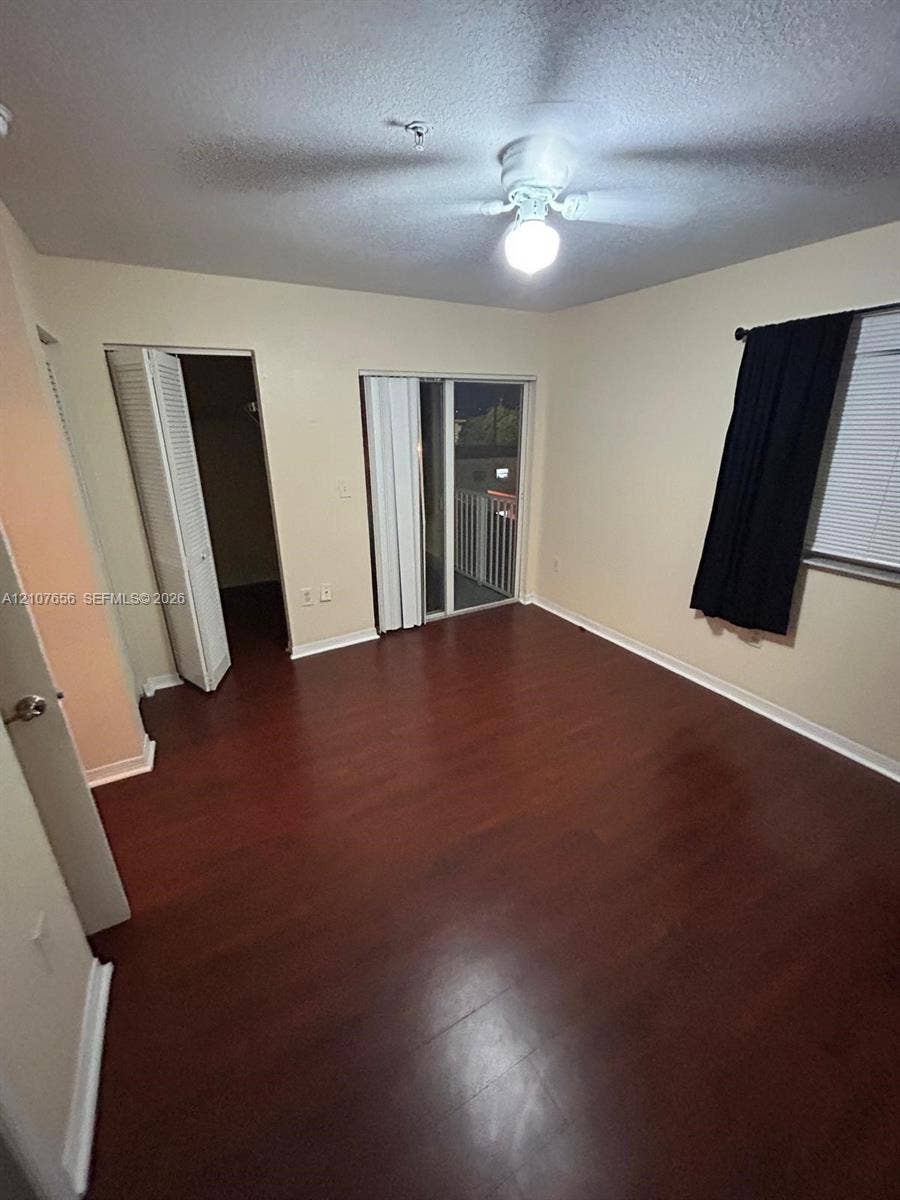 2088 NE 167th Street, #2-111, North Miami Beach, North Miami Beach, FL 33162 Wood-finish flooring, sliding glass door with balcony access, ceiling fan with light fixture, and closet with louvered doors