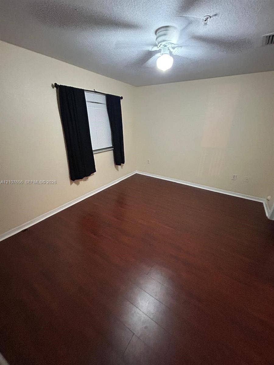 2088 NE 167th Street, #2-111, North Miami Beach, North Miami Beach, FL 33162 Interior space featuring dark wood-finish flooring, neutral wall tones, and a ceiling-mounted light fixture with an integrated fan