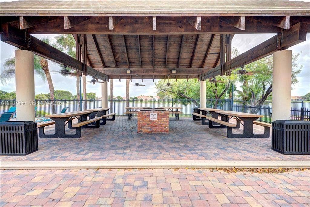 Covered pavilion featuring a vaulted timber-beam ceiling, exposed rafters, brick masonry grill island, and paver flooring