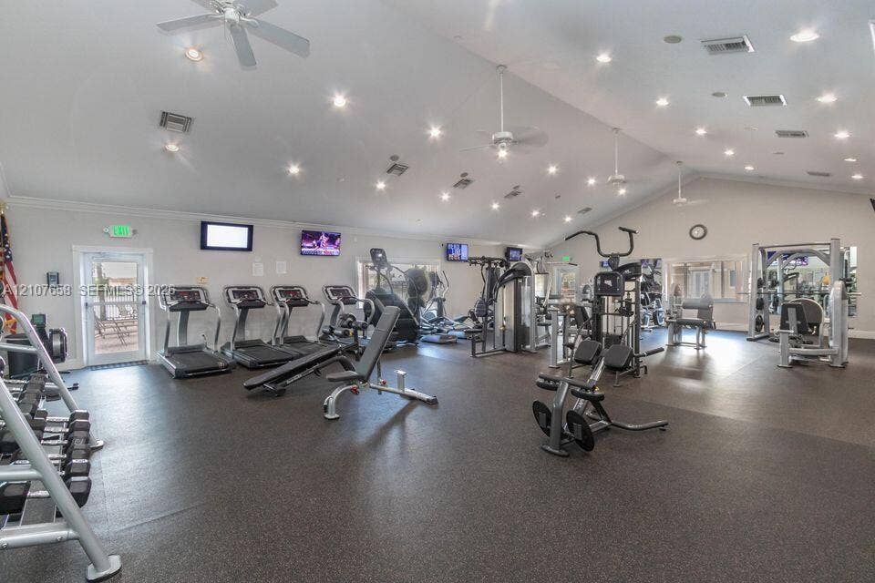 Fitness center featuring vaulted ceilings, recessed lighting, multiple ceiling fans, and impact-resistant rubber flooring