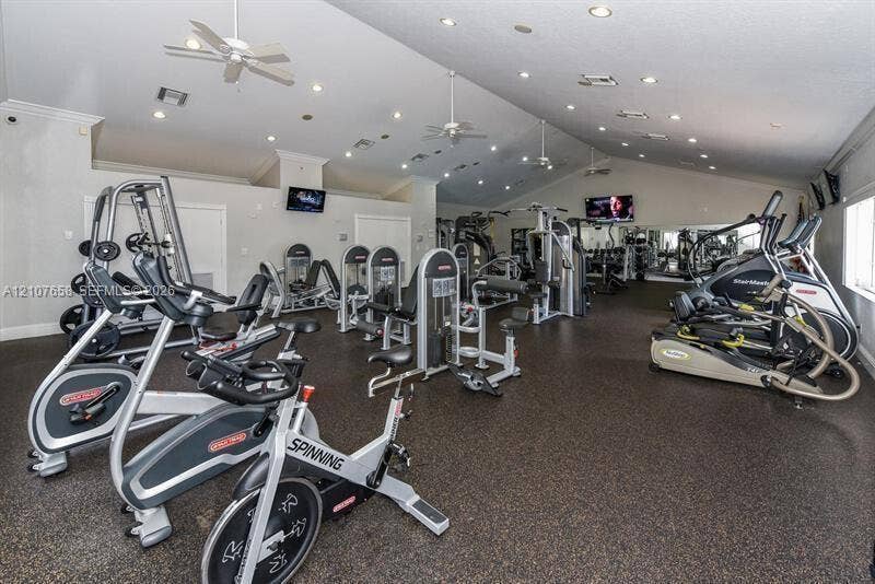 Fitness center featuring vaulted ceilings, recessed lighting, ceiling fans, and rubberized flooring