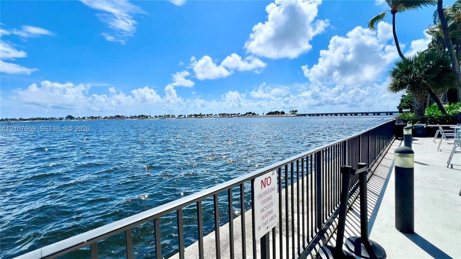 Waterfront promenade featuring a concrete bulkhead, metal perimeter railing, and integrated lighting fixtures