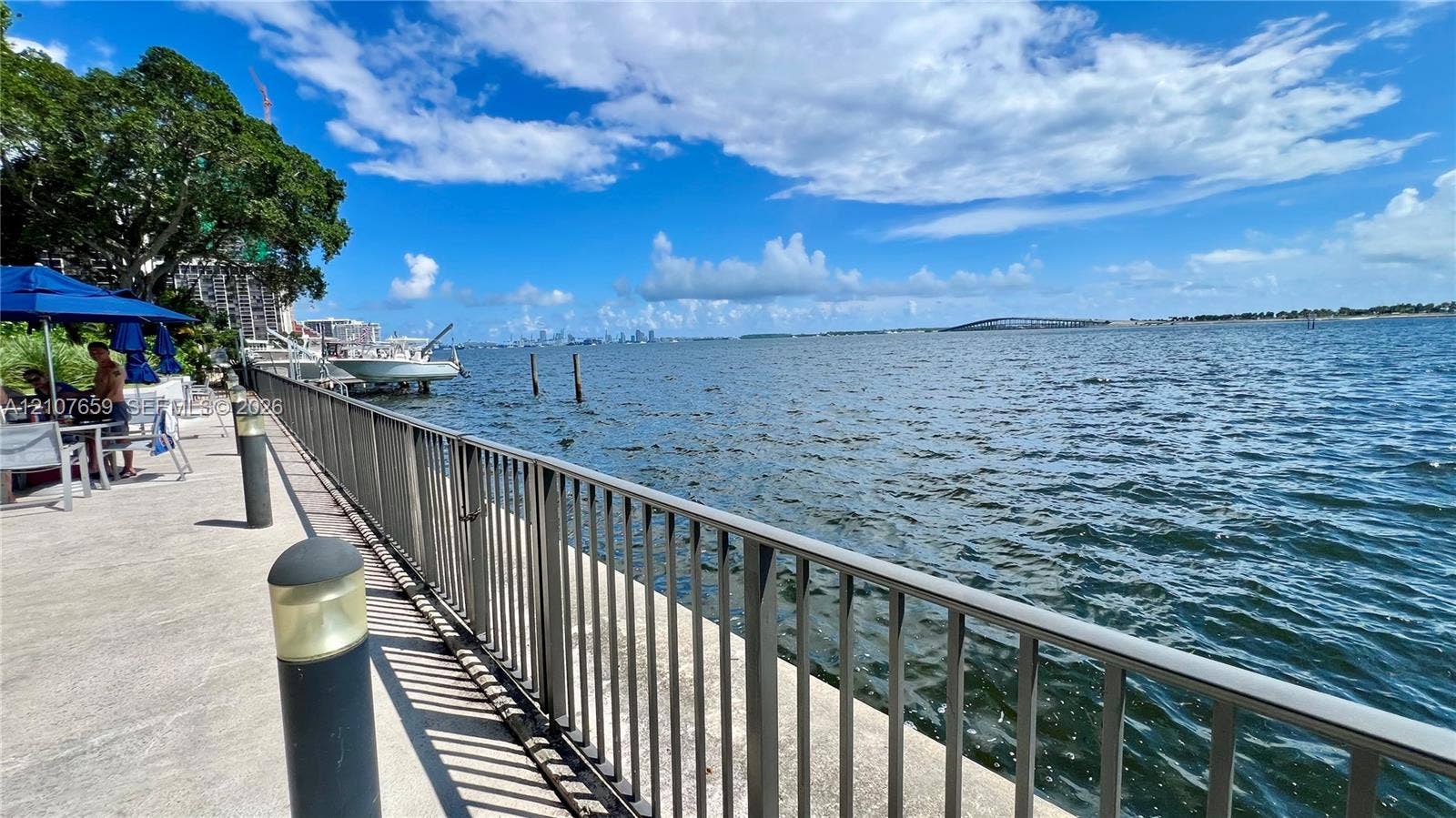 Waterfront concrete promenade featuring a metal safety railing, integrated pathway lighting, and direct bulkhead access to the waterway