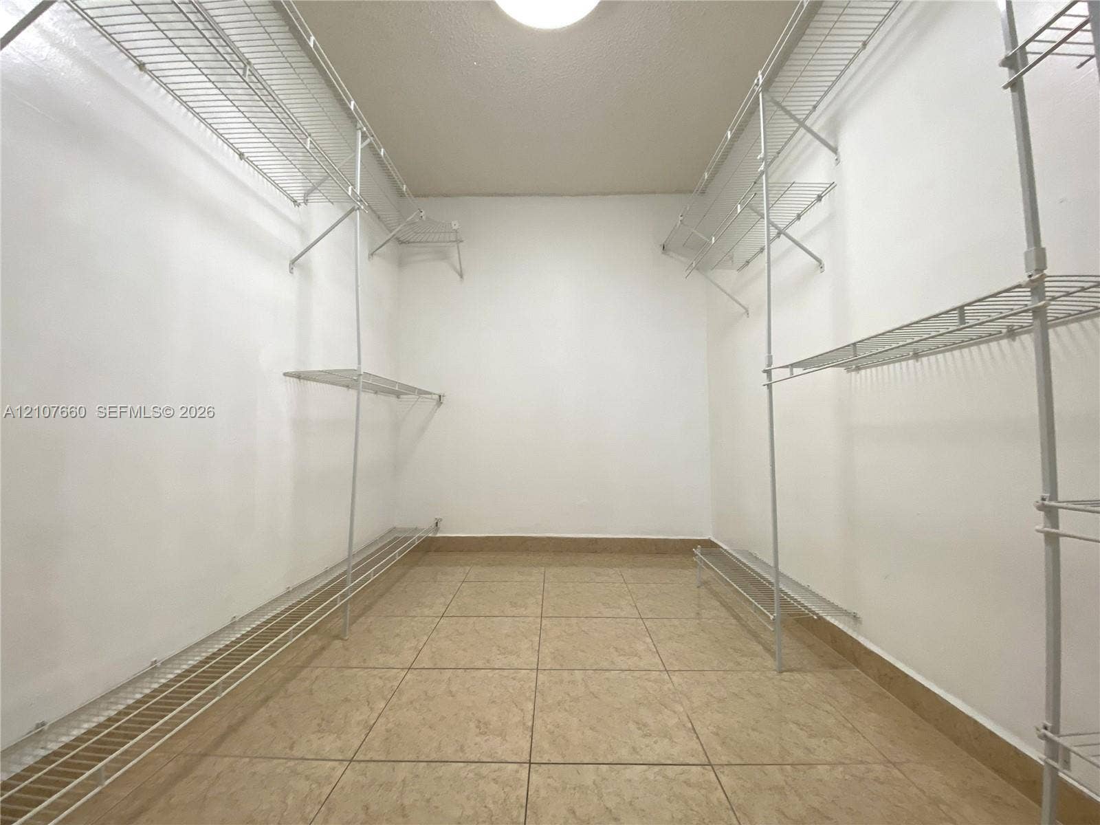 Walk-in closet featuring floor-to-ceiling white wire shelving and neutral tile flooring