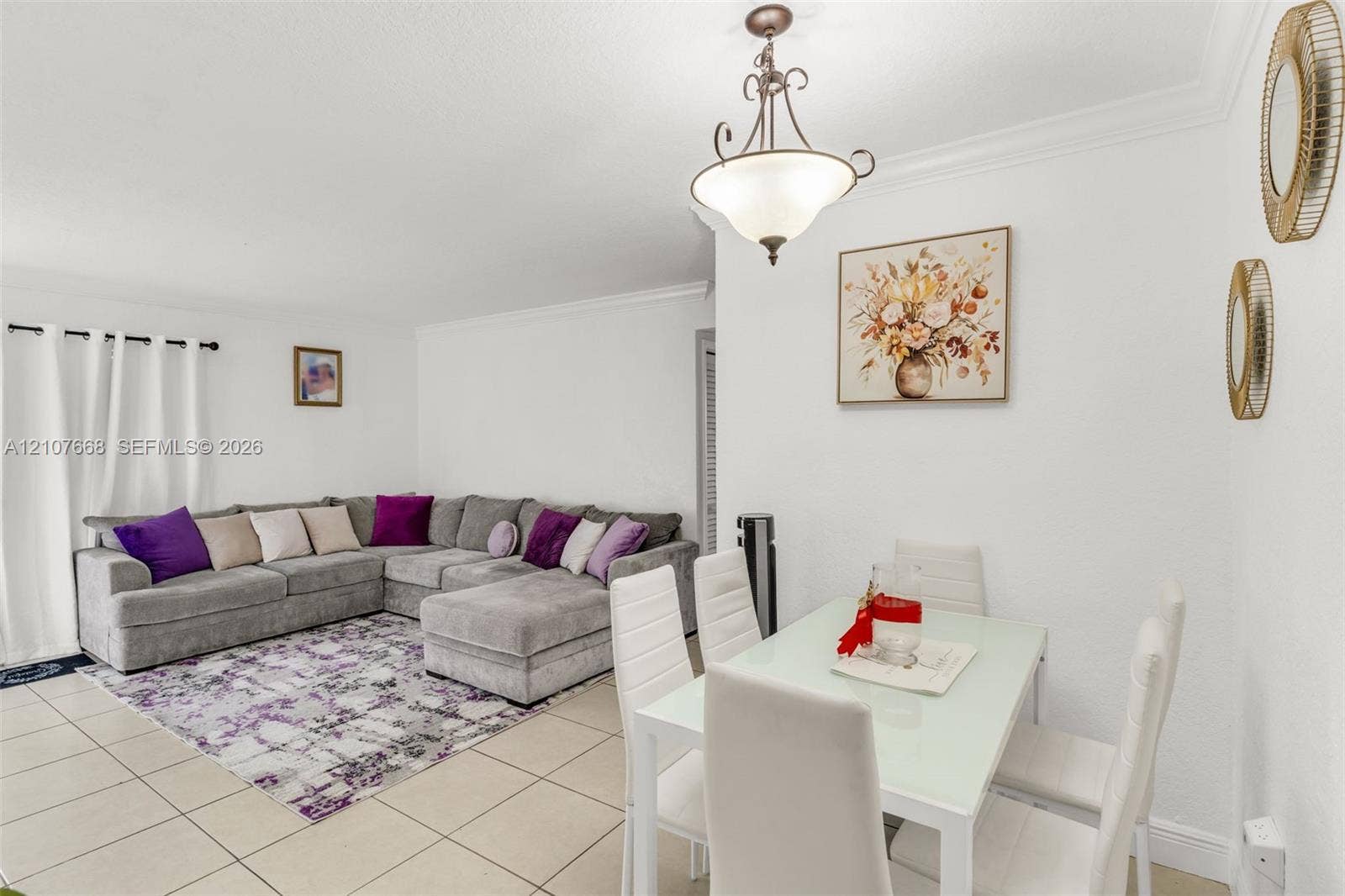 7245 SW 94th Place, #K4, Miami, FL 33173 Open living area featuring large-format tile flooring, crown molding, and a tiered metal chandelier with frosted glass shades