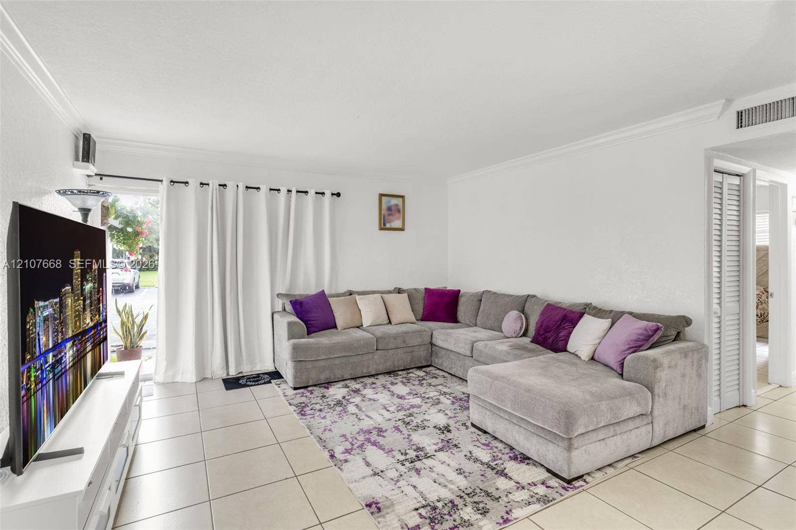 7245 SW 94th Place, #K4, Miami, FL 33173 Living space featuring neutral ceramic tile flooring, crown molding, and louvered closet doors