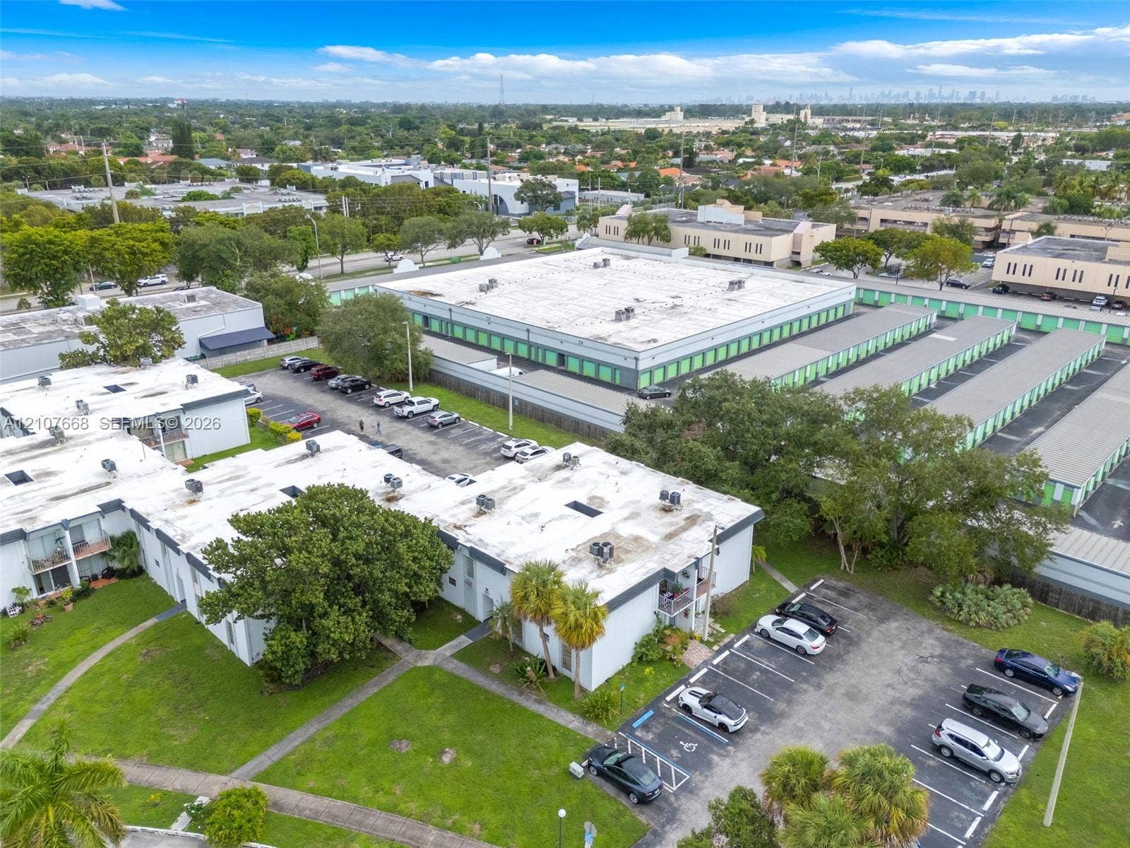 7245 SW 94th Place, #K4, Miami, FL 33173 Aerial perspective of multi-unit residential buildings featuring white exterior finishes, dedicated asphalt parking lots, manicured green space, and mature palm trees