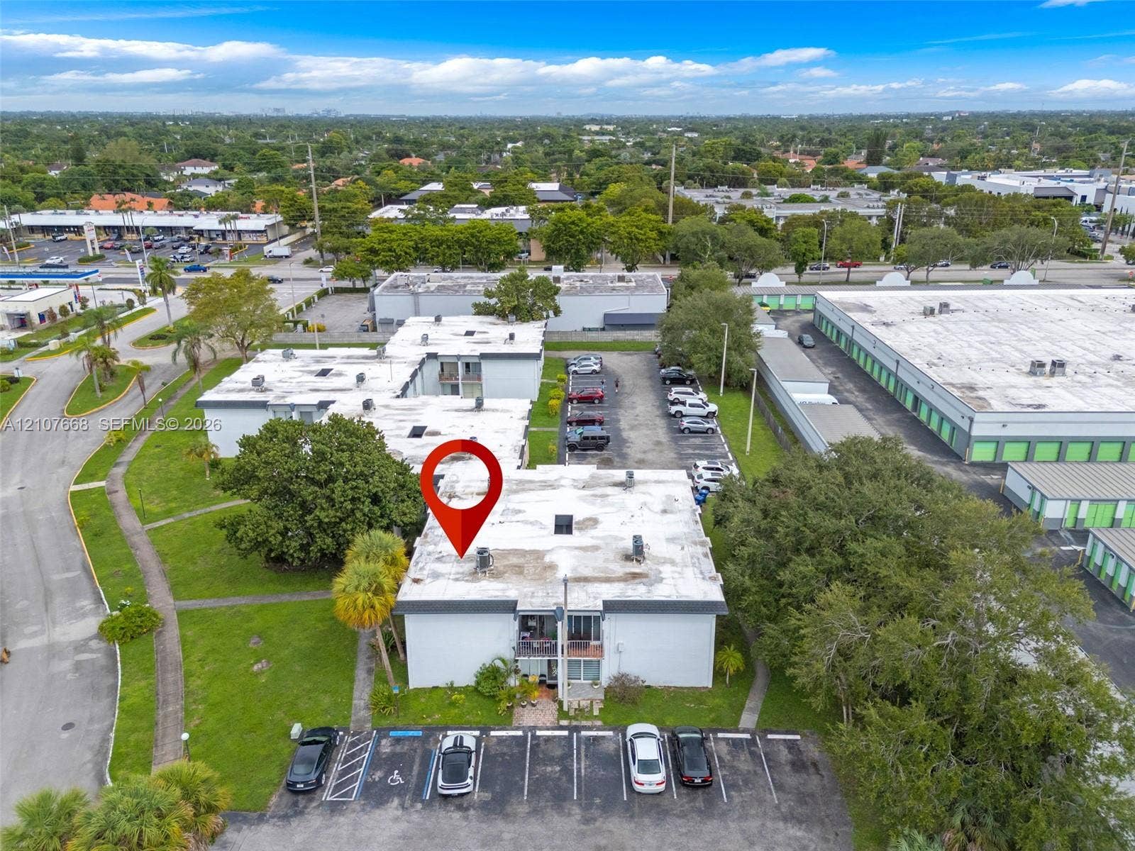 7245 SW 94th Place, #K4, Miami, FL 33173 Aerial perspective of a multi-unit property featuring flat roof construction, designated asphalt parking, ground-level landscaping, and mature palm trees