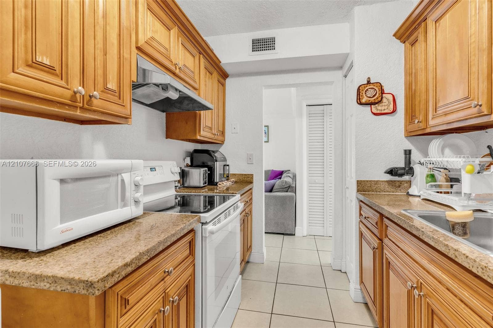 7245 SW 94th Place, #K4, Miami, FL 33173 Kitchen featuring shaker-style wood cabinetry, stone-finish countertops, tile flooring, and integrated white appliances
