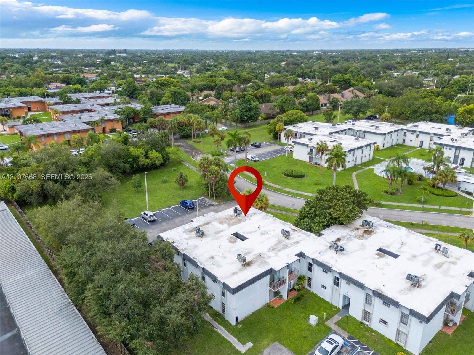 7245 SW 94th Place, #K4, Miami, FL 33173 Aerial view of the multi-unit building featuring a flat roof, dedicated surface parking area, and surrounding green space with mature landscaping