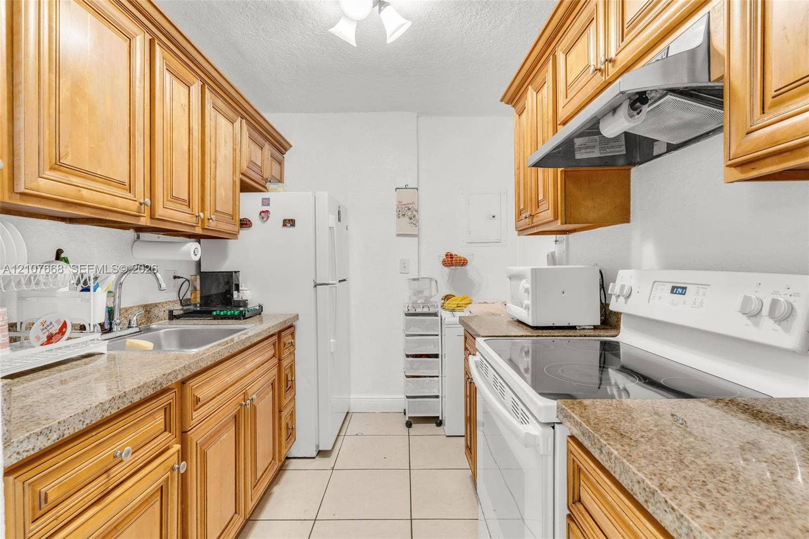 7245 SW 94th Place, #K4, Miami, FL 33173 Kitchen featuring natural wood cabinetry, stone-finish countertops, ceramic tile flooring, and a stainless steel sink with an arch-neck faucet