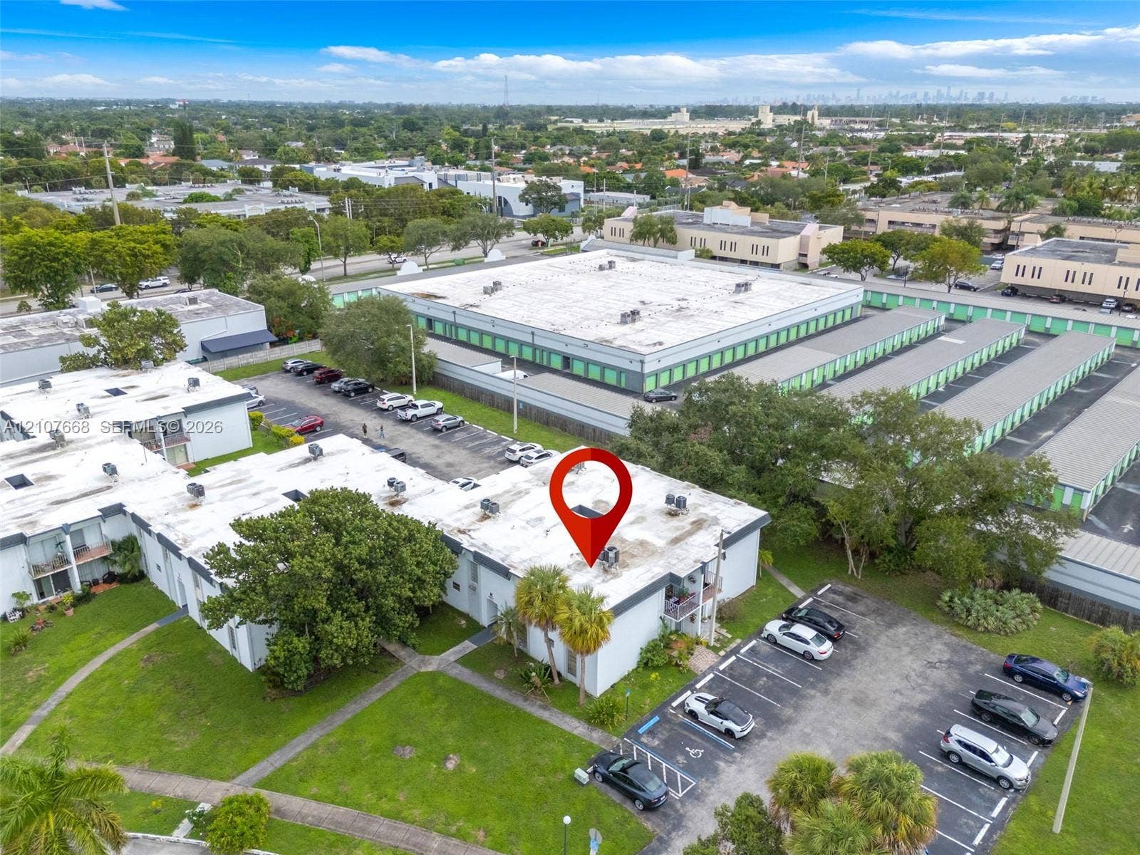 7245 SW 94th Place, #K4, Miami, FL 33173 Aerial perspective of a multi-unit property featuring flat roofing, dedicated asphalt parking, integrated exterior lighting, and landscaped green space
