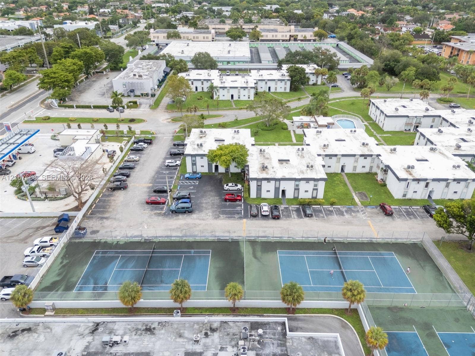 7245 SW 94th Place, #K4, Miami, FL 33173 Aerial perspective of residential complex featuring multiple tennis courts, dedicated asphalt parking, and landscaped green space