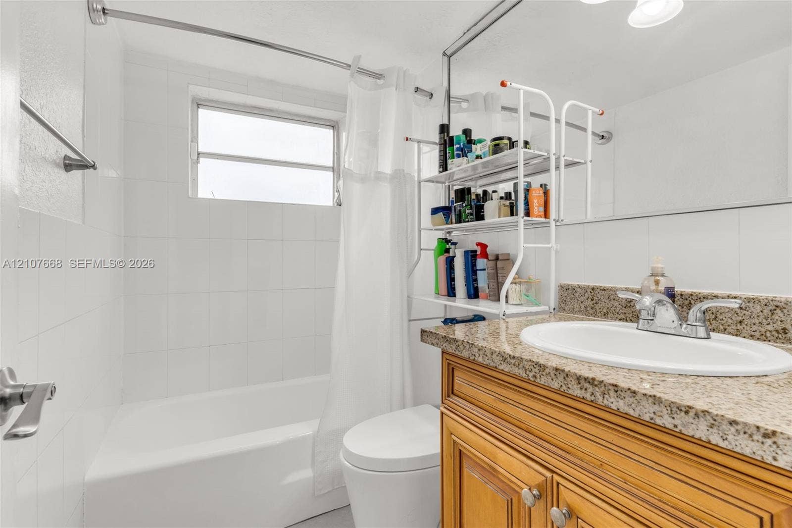 7245 SW 94th Place, #K4, Miami, FL 33173 Bathroom featuring a wood-finish vanity with a stone-composite countertop, integrated oval basin, white wall tile surround, and an oversized vanity mirror