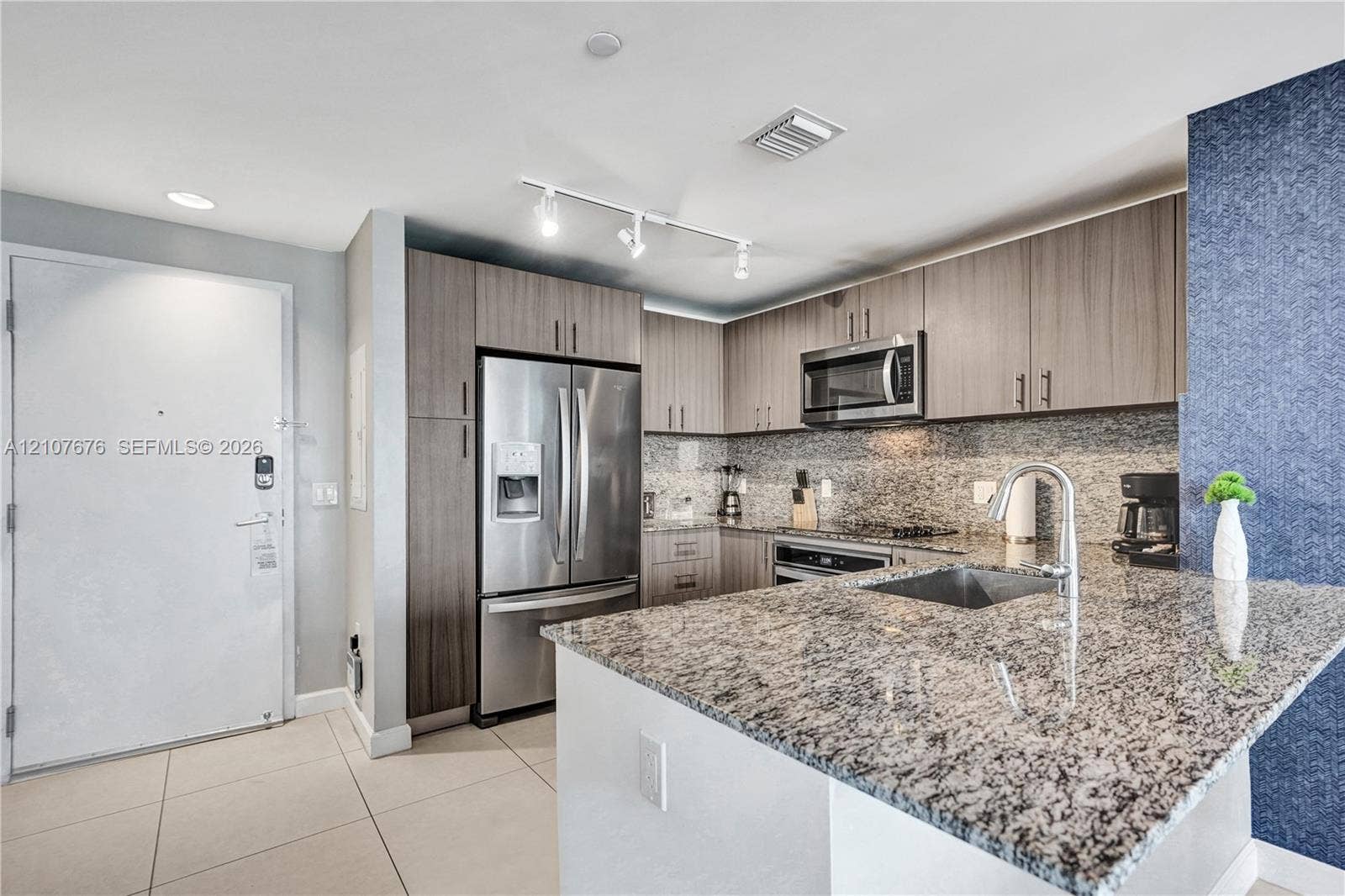 5350 NW 84th Avenue, #1004, Doral, FL 33166 Kitchen featuring stone countertops, stainless steel appliances, flat-panel cabinetry, track lighting, and a prep sink