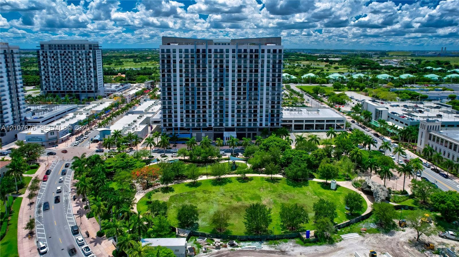 5350 NW 84th Avenue, #1004, Doral, FL 33166 High-rise residential building featuring a glass and concrete facade, integrated parking structure, and extensive green space with established landscaping