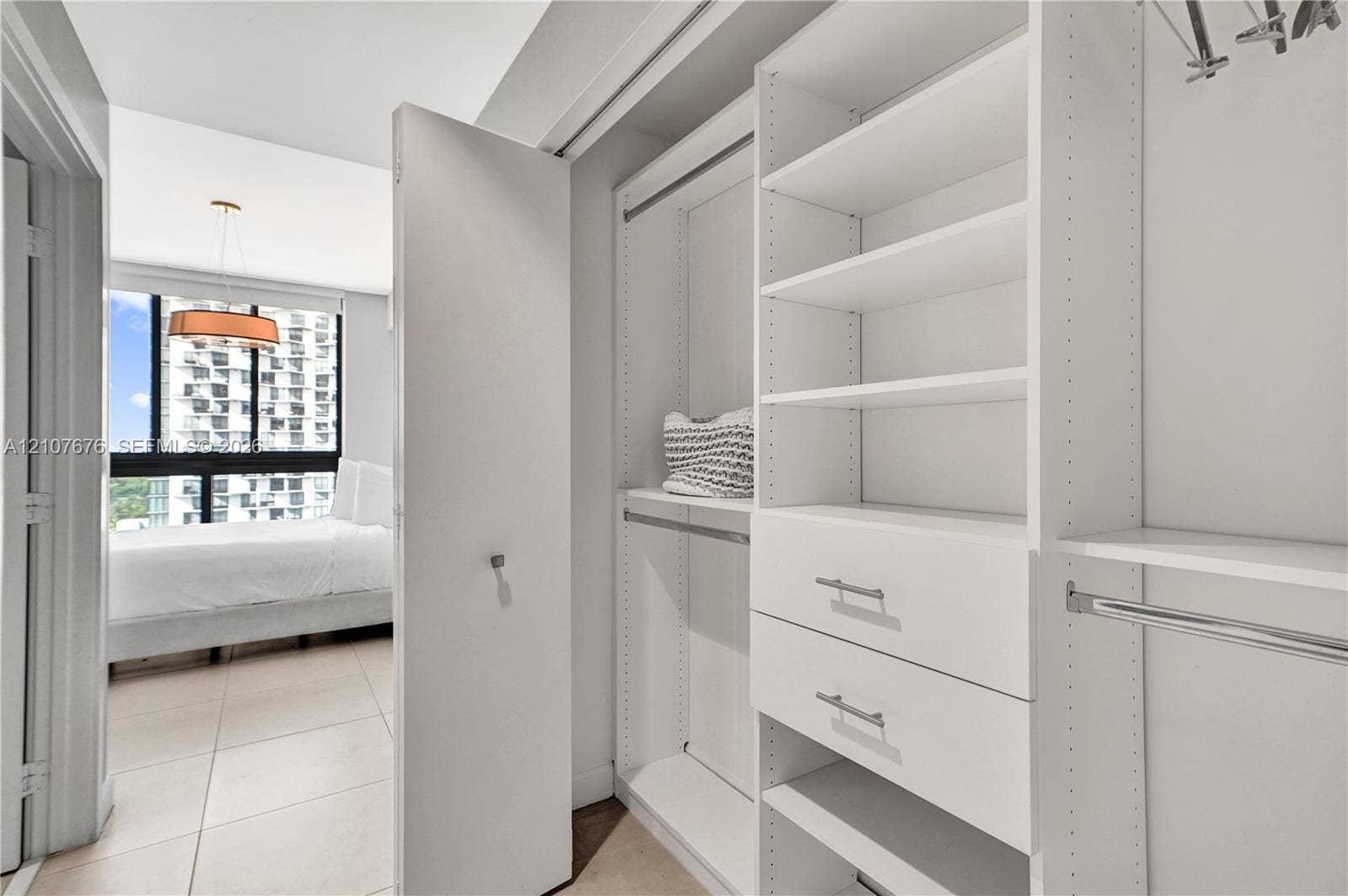 5350 NW 84th Avenue, #1004, Doral, FL 33166 Custom reach-in closet featuring white built-in shelving, dual soft-close drawers, metal garment rods, and integrated cabinetry hardware