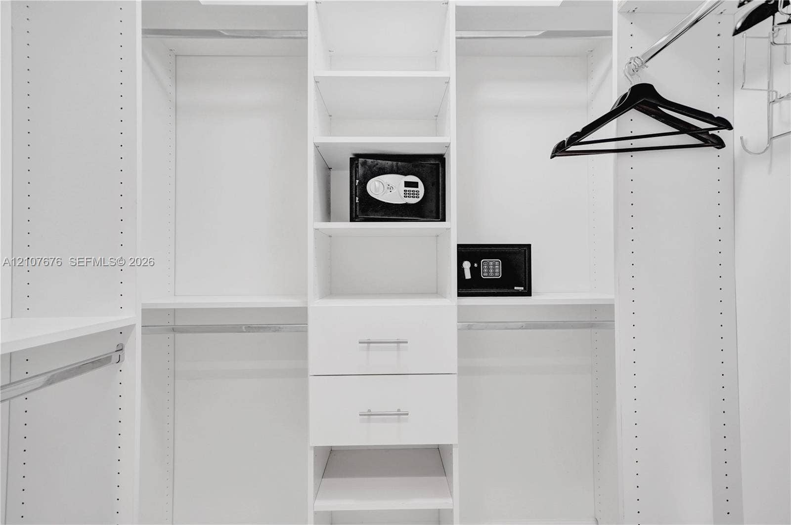 5350 NW 84th Avenue, #1004, Doral, FL 33166 Custom walk-in closet featuring white laminate built-in cabinetry, adjustable shelving, dual soft-close drawers with silver-tone pulls, and integrated garment rods