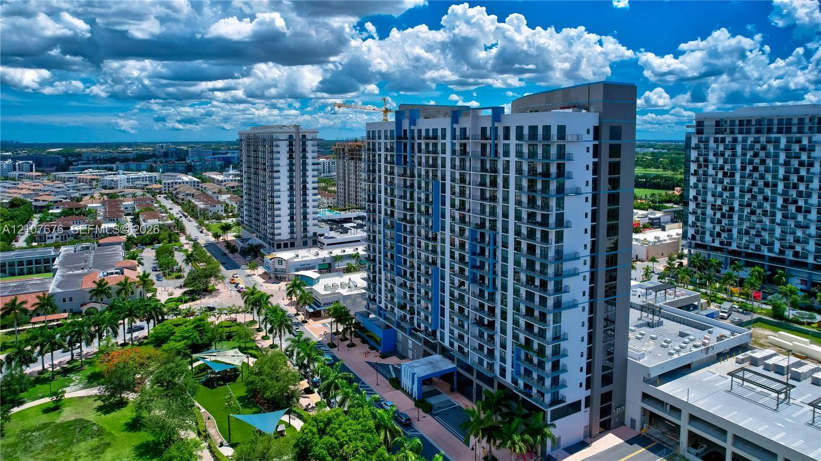 5350 NW 84th Avenue, #1004, Doral, FL 33166 High-rise architectural structure featuring a grid glass facade and individual balconies, situated in a dense urban environment with surrounding multi-story developments and paved pedestrian access