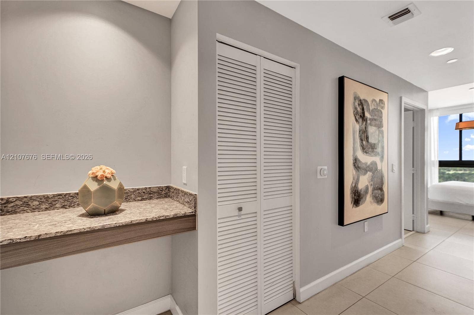 5350 NW 84th Avenue, #1004, Doral, FL 33166 Built-in stone-surface desk with wood-finish trim, bi-fold louvered closet doors, and large-format tile flooring