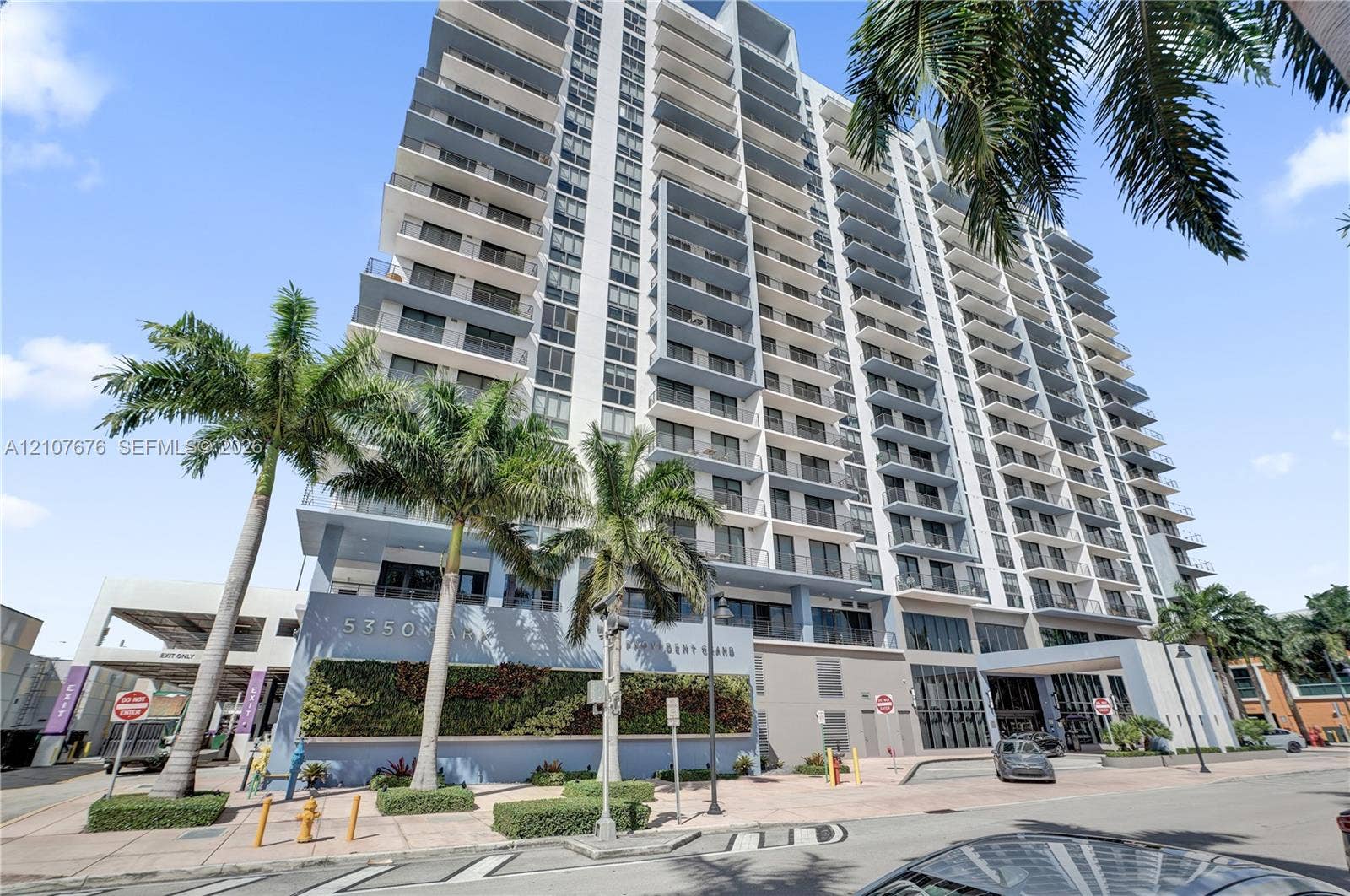 5350 NW 84th Avenue, #1004, Doral, FL 33166 High-rise exterior featuring private balconies, floor-to-ceiling glass paneling, a structured parking facility, and a vertical garden wall