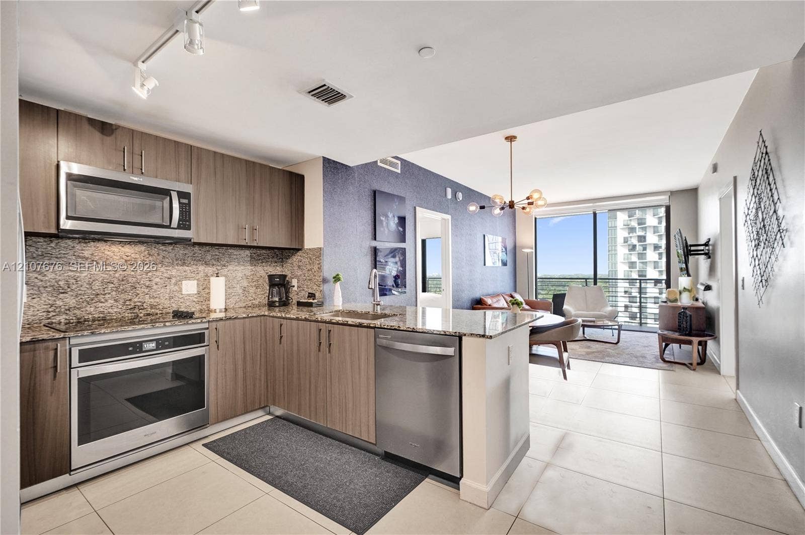 5350 NW 84th Avenue, #1004, Doral, FL 33166 Kitchen featuring wood-finish cabinetry, stone-surface countertops, stainless steel appliances, track lighting, and tile flooring