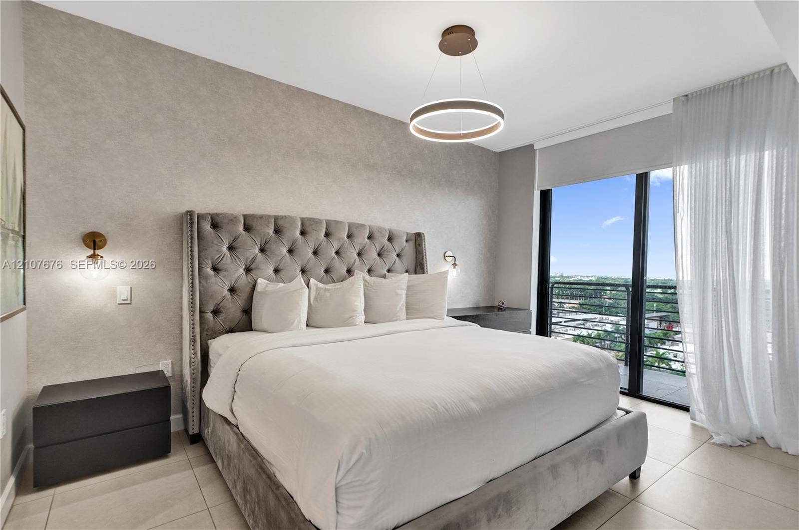 5350 NW 84th Avenue, #1004, Doral, FL 33166 Textured feature wall, modern circular LED pendant lighting, wall-mounted globe sconces, large-format tile flooring, and floor-to-ceiling glass doors opening to a balcony